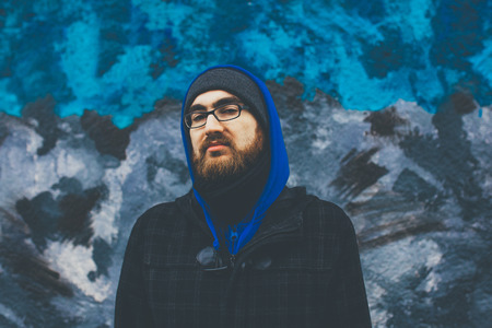 Portrait of bearded young man wearing winter clothes and eyeglasses outdoors.のeditorial素材