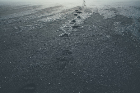 Footprints on a black sand beach in Iceland. Concept for loneliness, solitude, depression.の写真素材