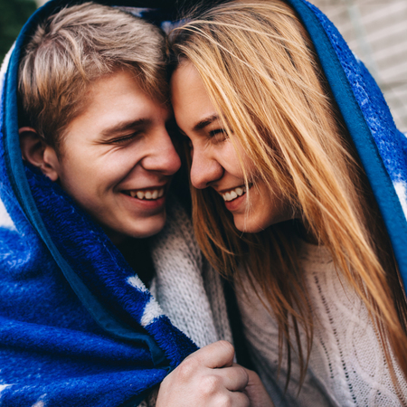 Close-up portrait of laughing hipsters couple in love. Young boy and girl smiling together outdoors.の写真素材