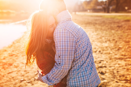 Young couple near lake having good time at sunsetの写真素材
