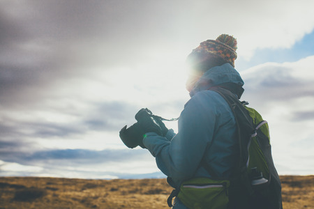 Back view of woman wearing winter clothes taking pictures on sunset in Iceland.の写真素材