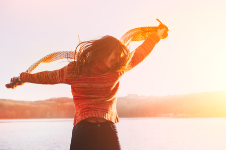 Positive young girl wearing warm winter clothes having fun at lake.の写真素材