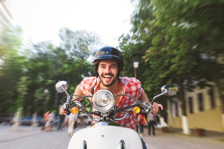 Smiling Young Man Riding Motor Scooter in the city. Speed motion blur concept.の写真素材