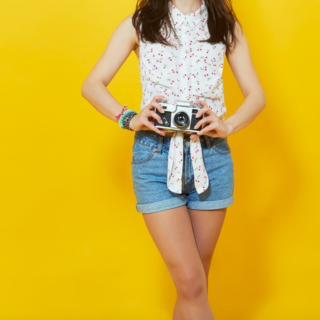 girl with camera. Cropped unrecognizable image of a young woman standing with a camera over a...
