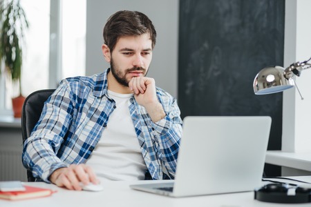 Handsome businessman working with laptop in officeの写真素材