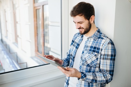 young stylish hipster man using tablet on the house balconyの写真素材