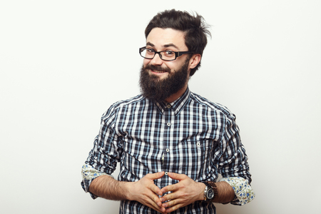 Young hipster man with beard and sunnglasses posing and looking to the camera isolated over white background in studioの写真素材