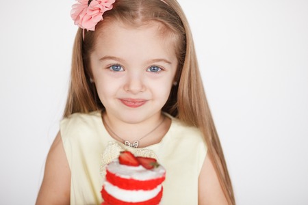 Little girl celebrating her birthday. Closeup cute child girl holding a red velvet mini cake with...