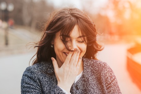 Happy laughing beautiful large woman. Close up plus size girl smiling on a cold autumn day with lens flare effectの写真素材