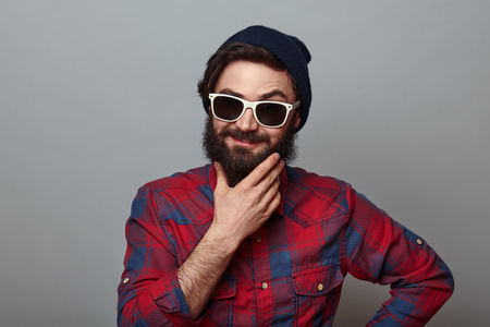 Thoughtful bearded man smiling and hesitating. on grey backgroundの写真素材