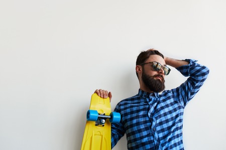 close up of bearded hipster in checkered shirt holding yellow skateboard isolated over white background with copy spaceの写真素材