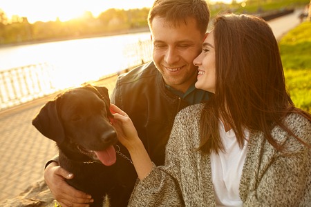 Happy family of two resting at a picnic in the park with a dogの写真素材