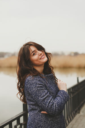 Vertical portrait close up of young beautiful brunette woman wearing a coat on fallの写真素材