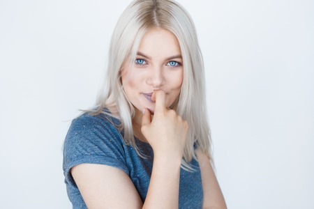 Closeup portrait of a sensual young blond woman over white background. Teenage girl with blue eyes and bleached silver hairの写真素材
