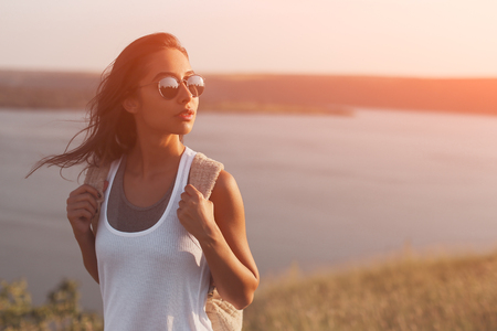female traveler portrait with backpack and sunglasses. applied filter effect. Young woman with windy hairtravelingの写真素材