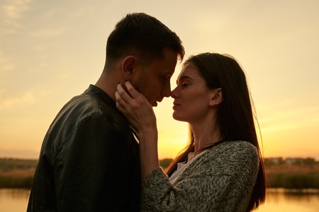 sillhouette of young couple in love kissing at sunset