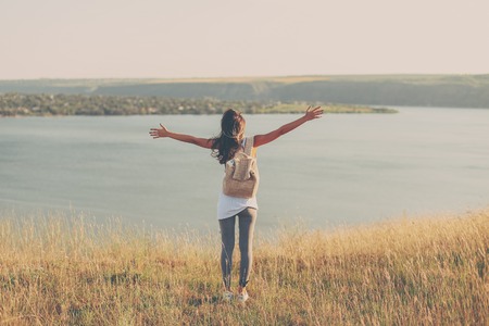 Back view of Woman Traveler with hands raised hiking Travel Lifestyle concept. Summer vacations outdoorの写真素材