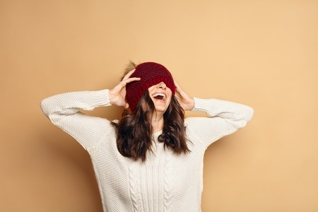 Funny Hipster Girl in Knitted Sweater and Beanie Hat. Laughing young woman in Trendy casual cozy...