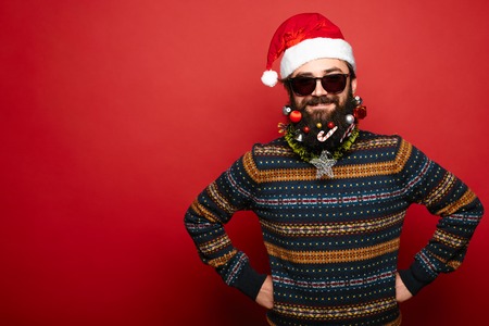 Christmas man in Santa Claus hat and sunglasses over red background with empty spaceの写真素材