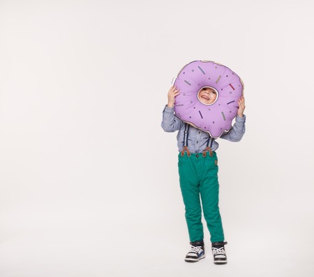 little boy holding a big pillow in shape of donutの写真素材