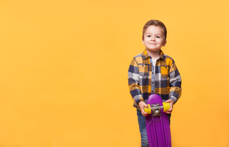 smiling little boy standing with skateboardの写真素材