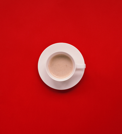 From above view of white cup of coffee on red background.の写真素材