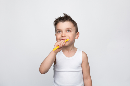 Small kid brushing teeth on whiteの写真素材