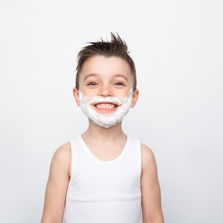 Smiling boy with shaving foam on faceの写真素材