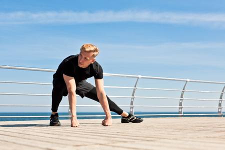 Sportsman stretching body on pierの写真素材