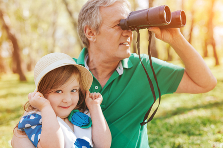 Grandfather with binocular and little girlの写真素材