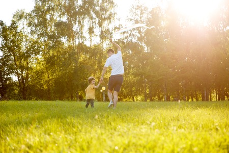 Father and son running away on meadowの写真素材