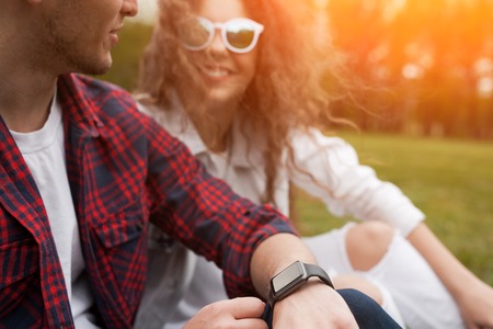 Couple sitting on grass on sunny dayの写真素材