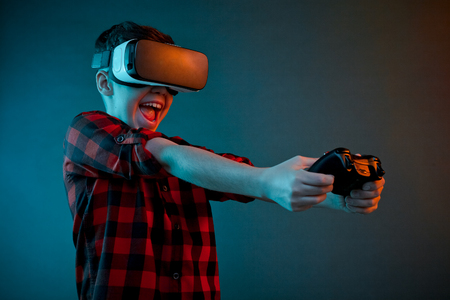 Excited boy playing gamepad in VR glassesの写真素材
