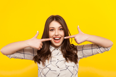 Woman smiling and pointing at mouthの写真素材