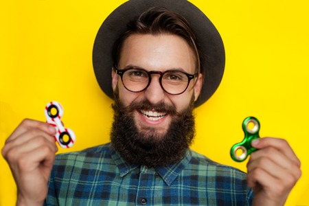 Happy smiling hipster man with fidget spinnersの写真素材