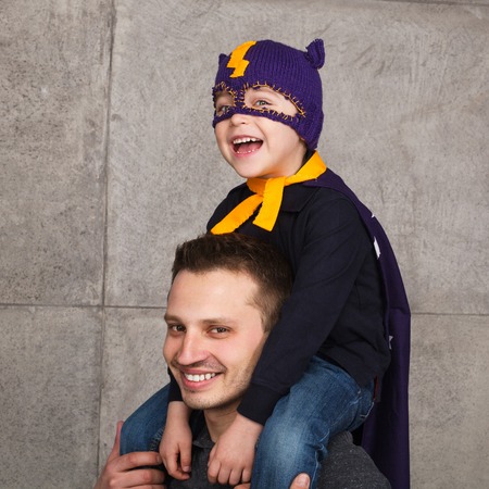Boy in hero costume on fathers shoulders