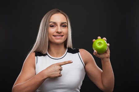 Sporty beefy woman holding green appleの写真素材