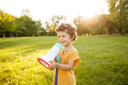 Young boy standing in park holding loudspeakerの写真素材