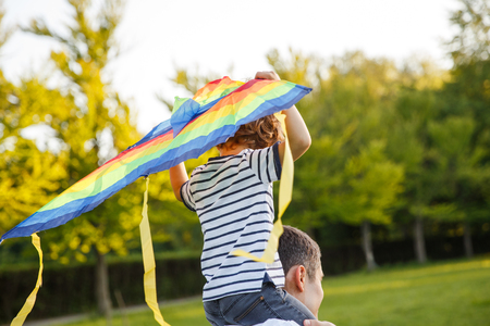 Boy sitting on fathers shoulders playingの写真素材