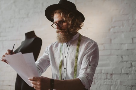 Bearded man in hat holding sheetsの写真素材