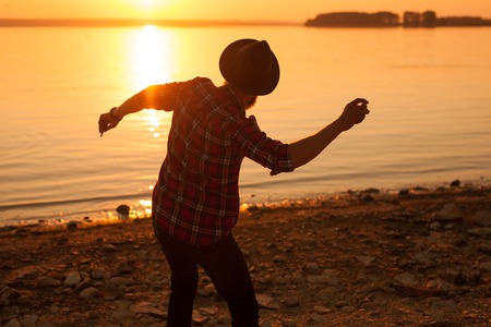 Hipster throwing pebble to waterの写真素材