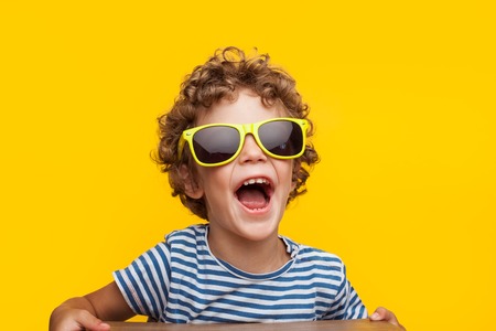 Adorable kid in bright sunglasses on orangeの写真素材