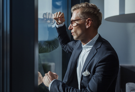 Dreaming stylish man posing near windowの写真素材