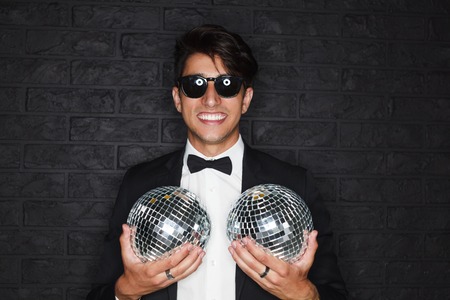 Cheerful man posing with disco ballsの写真素材