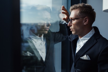 Thoughtful businessman at windowの写真素材