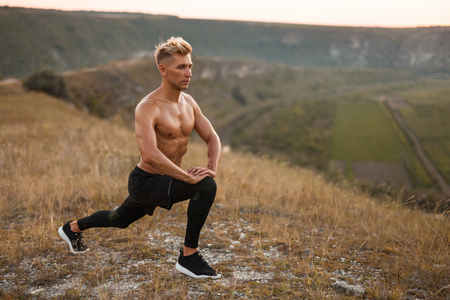 Bare-chested man lunging in natureの写真素材