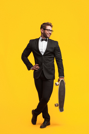 Man in suit holding skateboardの写真素材