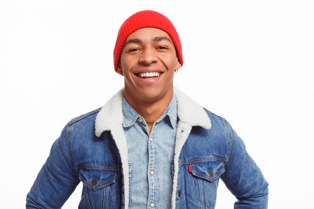 Handsome African-American man in stylish outfit smiling and looking at camera while standing on...