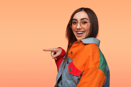 Cool girl in glasses pointing awayの写真素材
