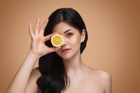 Pretty woman with slice of orange in studioの写真素材